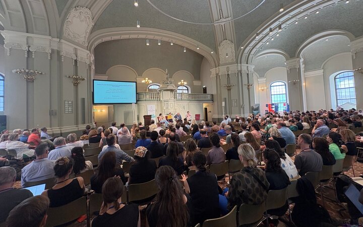 Innenaufnahme der Französischen Friedrichstadtkirche mit vollen Sitzreihen und einem Podium