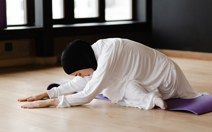 Young Muslim lady stretching in contemporary studio