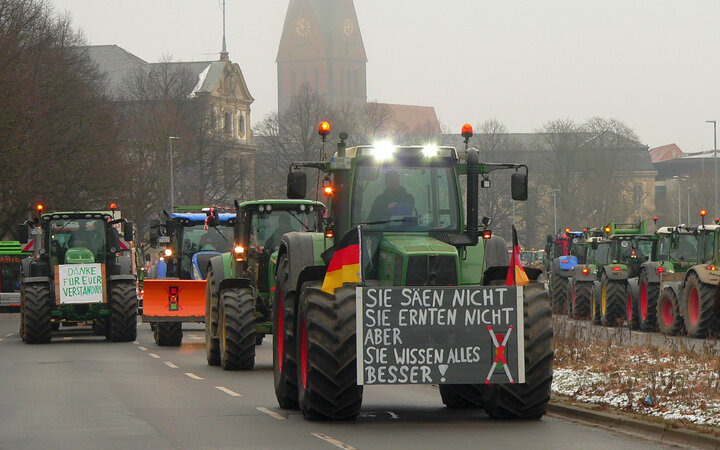 Kolonnen von Traktoren, teils mit Protestschildern