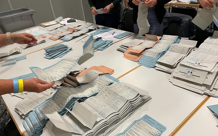 Auszählung von Stimmzetteln auf einem großen Tisch