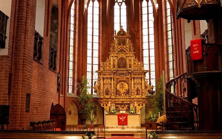 Innenraum einer Backsteingotik-Kirche mit prunkvollem Altar