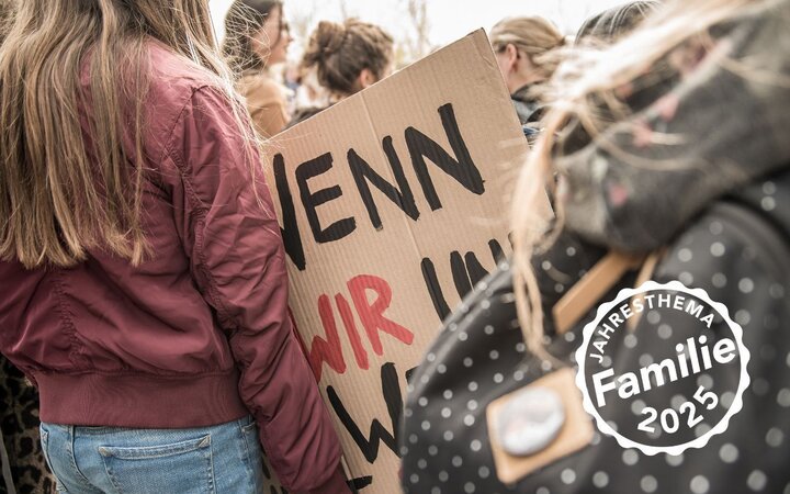 Foto von Kindern mit einem von Hand beschriebenen Pappschild mit Demo-Slogan
