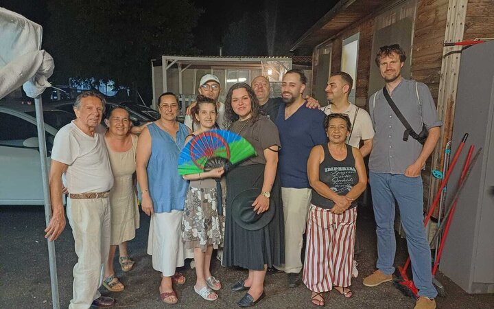 Gruppenfoto vor einem kleinen Haus mit einer Fassade aus einfachen Holzbrettern