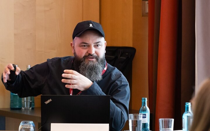 Cemal Öztürk gestikulierend am Laptop vor Publikum