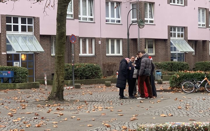 Gruppe Jugendlicher auf einem Gehweg vor Mehrfamilienhäusern