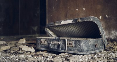 Weathered suitcase inside an abandoned destroyed house