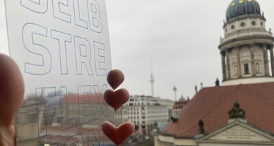 Spiegelnde Postkarte mit dem Schriftzug "Selbstreflexion" und einer Kirche