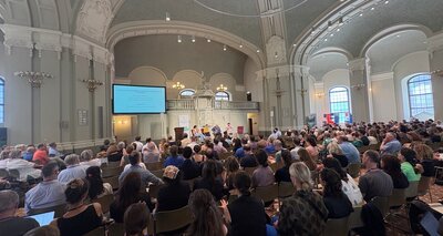 Innenaufnahme der Französischen Friedrichstadtkirche mit vollen Sitzreihen und einem Podium